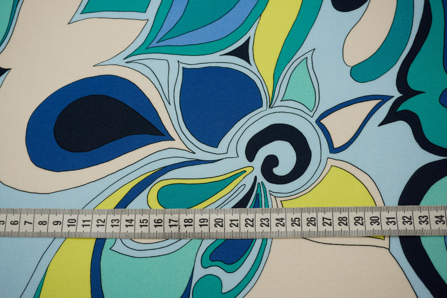 Detailaufnahme des grafisch-floralen Musters auf Viskose mit Maßband – farbintensive Details, weiche Oberfläche und fließender Fall