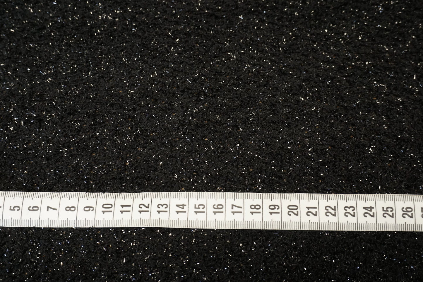 Glamour-Strickstoff in Tiefschwarz mit glitzernden Lurexfäden Nahaufnahme mit Maßband