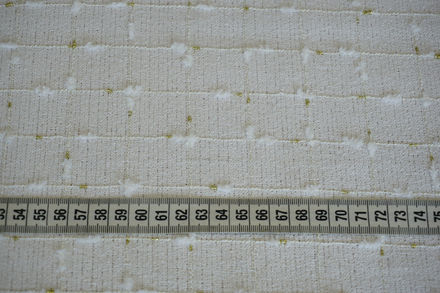 Bouclé-Stoff in Weiß und Gold mit geometrischem Muster mit Maßband und als Nahaufnahme