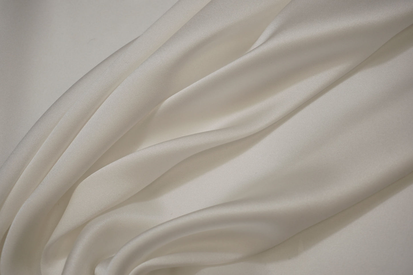 Detailaufnahme italienischer Seidensatin – seidiger Glanz, glatte Textur, weich und fließend, ideal für hochwertige Brautkleider und elegante Mode