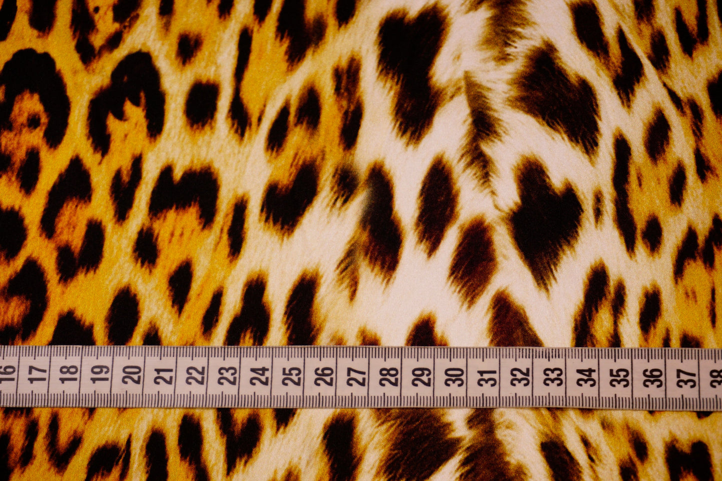 Detailaufnahme des Animalprints auf Seidensatin mit Maßband – edler Glanz, warme Farbtöne und luxuriöse Textur