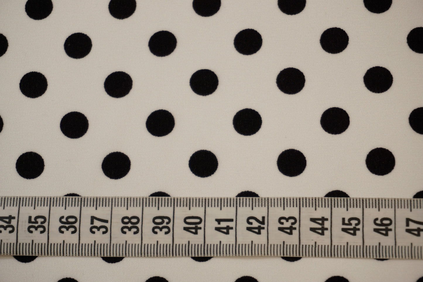 Detailaufnahme der dunkelblauen Punkte auf Seidencrêpe mit Maßband – elegante Textur und klassische Optik