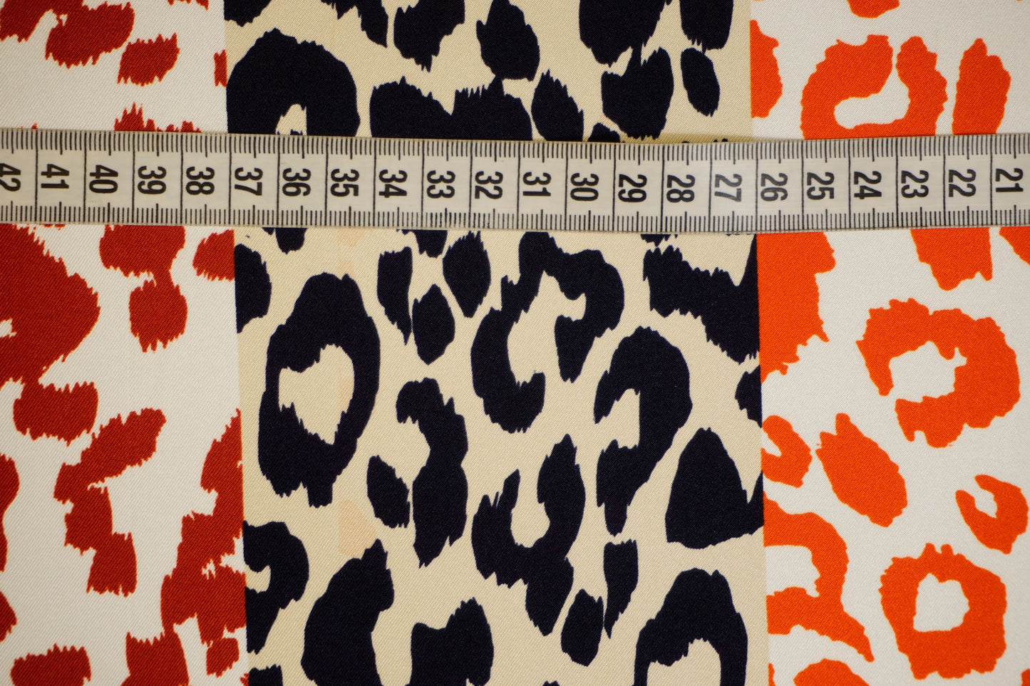 Italienischer Seidentwill mit Animalprint in Orange, Rot und Schwarz Nahaufnahme mit Maßband