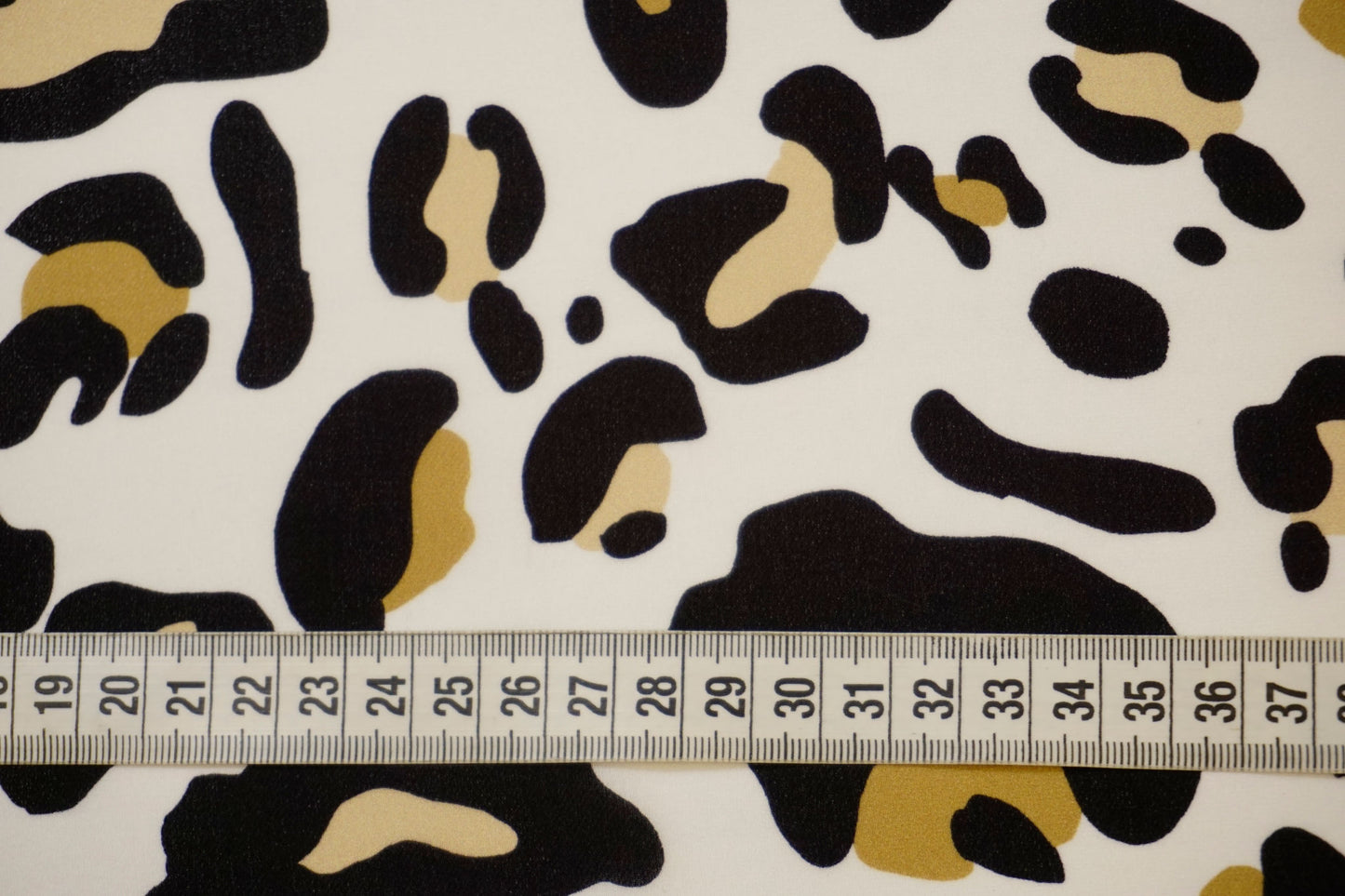Detailaufnahme des stilisierten Leoprints auf Seidencrêpe mit Maßband – edle Struktur und trendiger Look