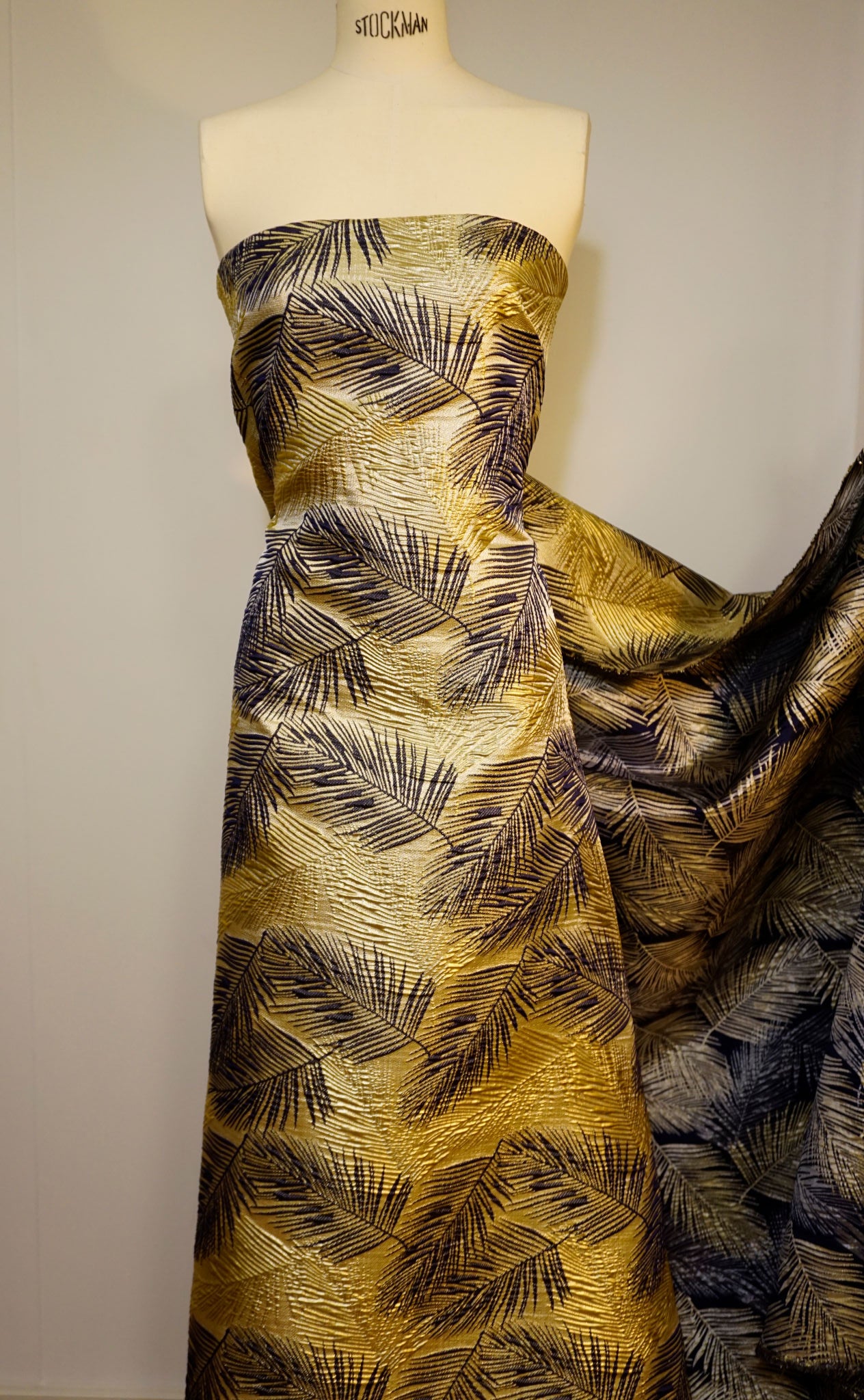 Detailaufnahme des Brokats – erhabene Webstruktur, glänzende Lurex-Fäden und kunstvolles Palmenmuster an Schneiderpppe als Kleid drappiert