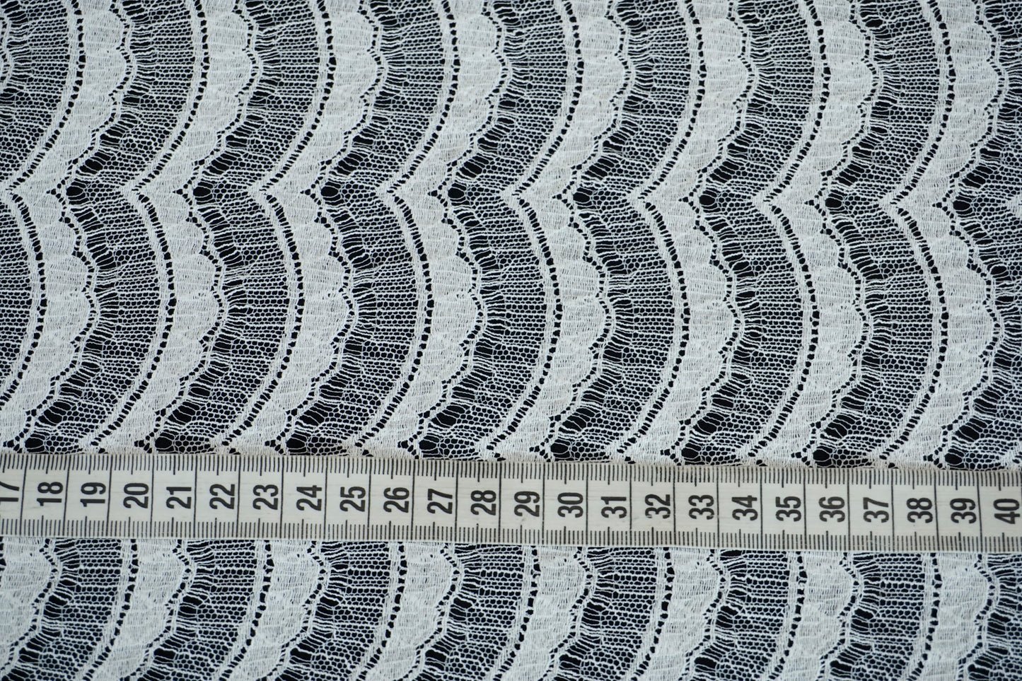 Nahaufnahme der französischen Spitze mit feiner, wellenförmiger Struktur und eleganter Transparenz