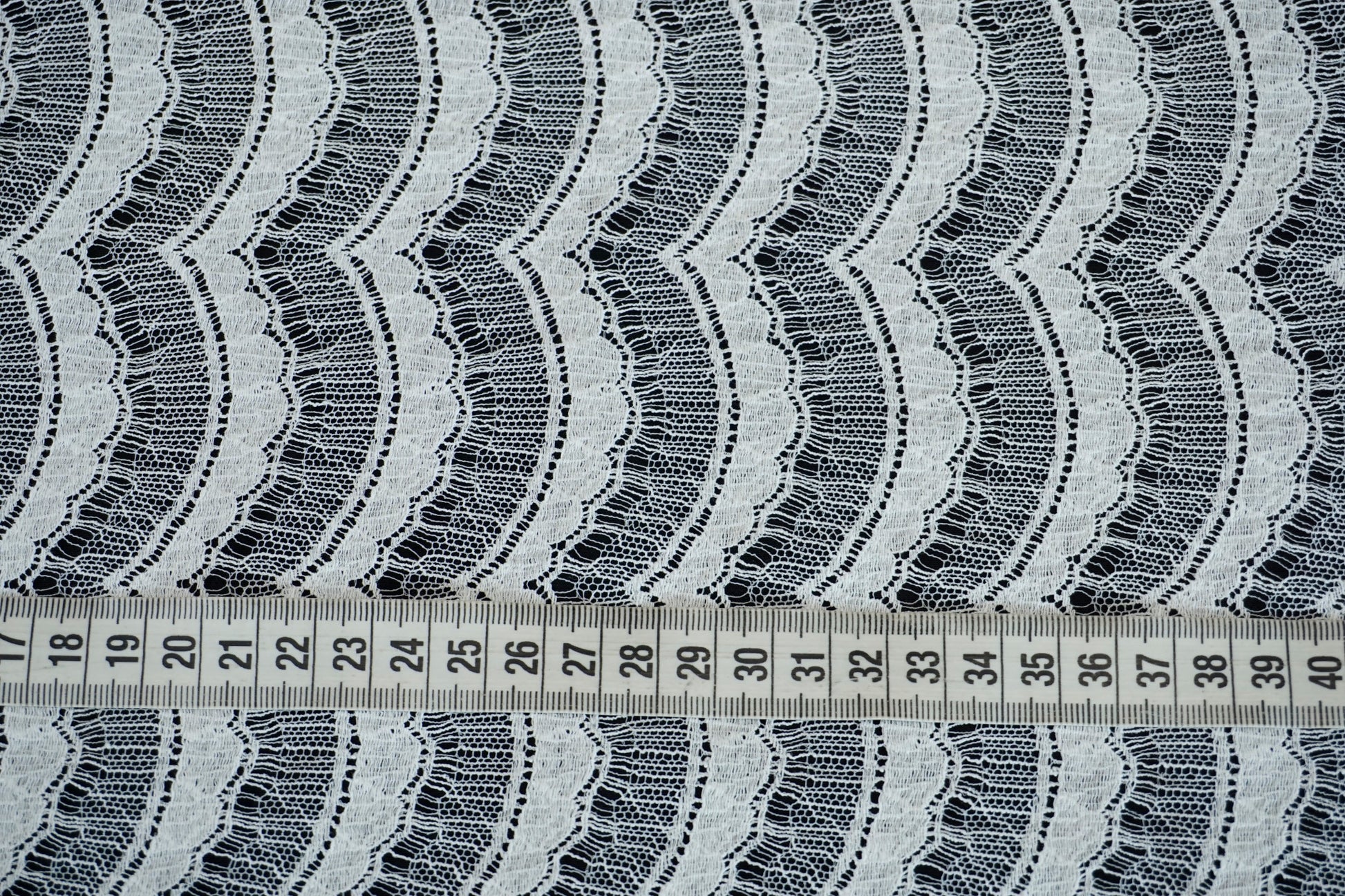 Nahaufnahme der französischen Spitze mit feiner, wellenförmiger Struktur und eleganter Transparenz