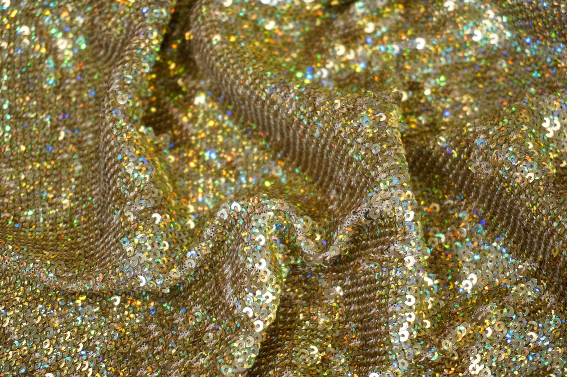 Nahaufnahme der dicht gesetzten goldenen Pailletten mit holografischem Farbspiel